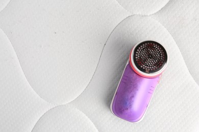 Fabric shaver on mattress with lint, top view. Space for text