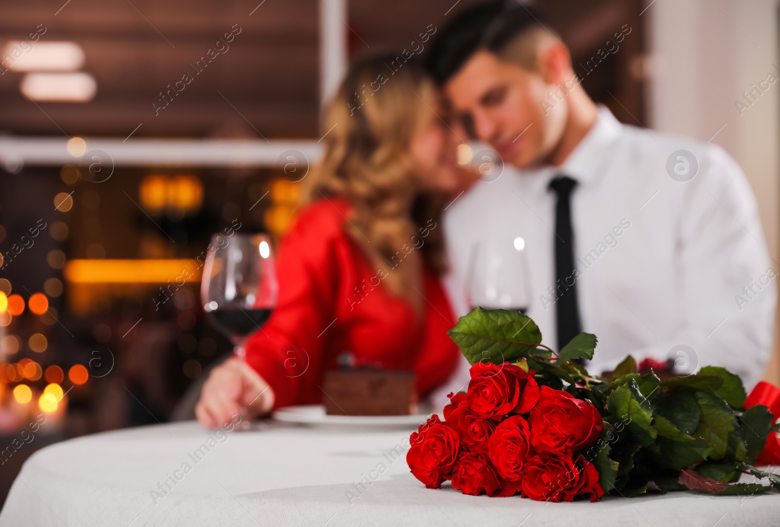 Photo of Lovely couple celebrating Valentine's day in restaurant, focus on table with red roses