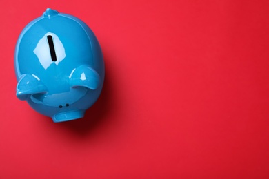 Photo of Top view of piggy bank on red background, space for text. Money savings