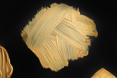 Photo of Golden paint brush strokes on black background