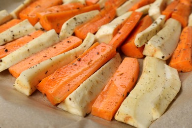 Photo of Baking tray with parchment, parsnips and carrots, closeup