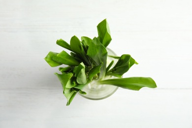 Glass of wild garlic or ramson on white wooden table, top view