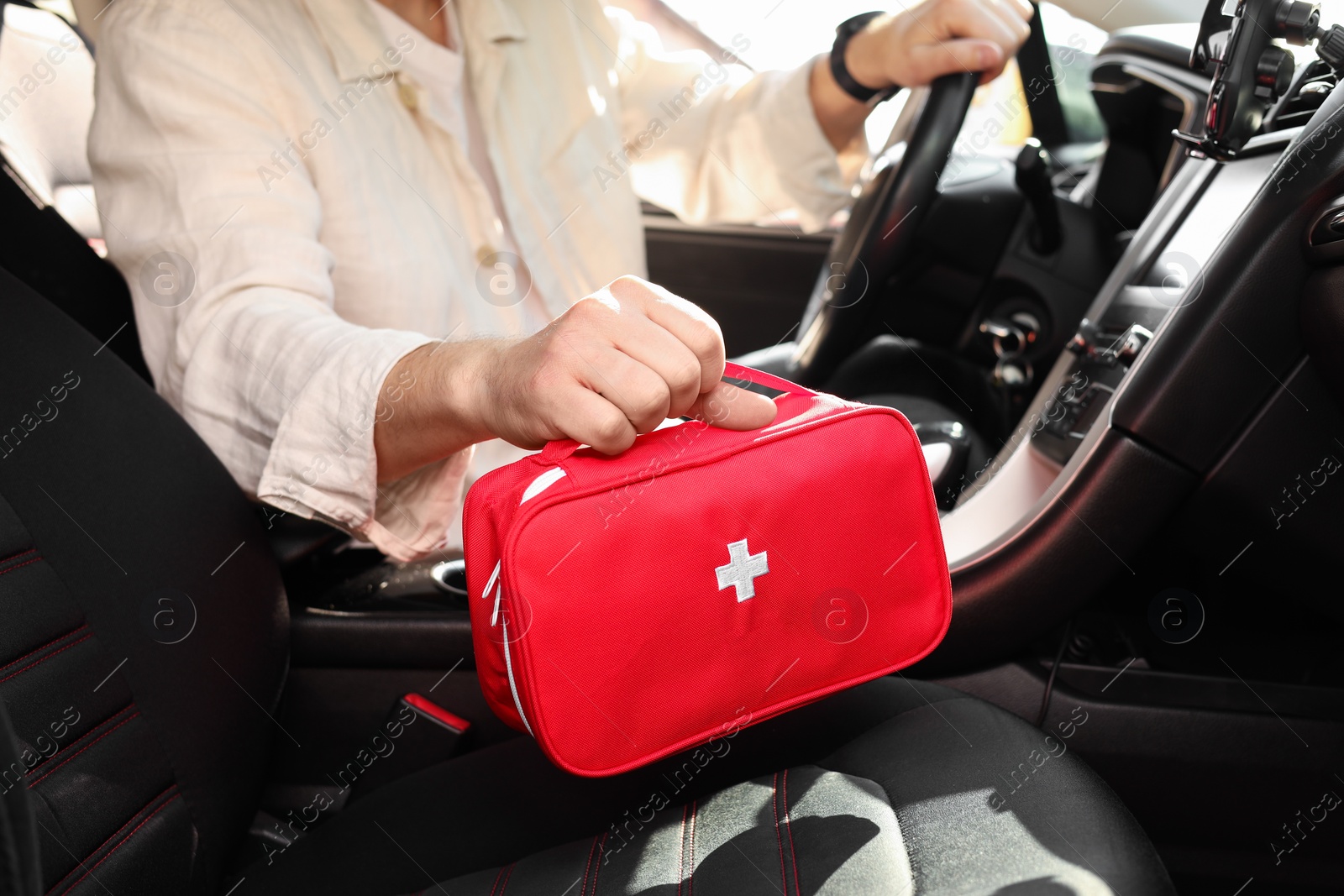 Photo of Man with first aid kit inside car, closeup