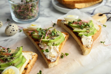 Photo of Tasty toasts with avocado, quail egg and chia seeds served on board