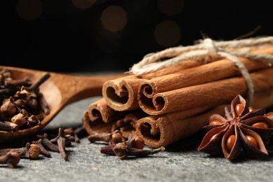 Photo of Different spices on gray table against black background, closeup