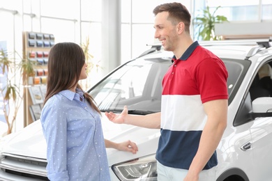 Photo of Young couple near auto in salon. Buying new car