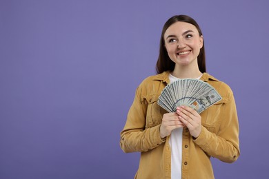 Happy woman with dollar banknotes on purple background, space for text