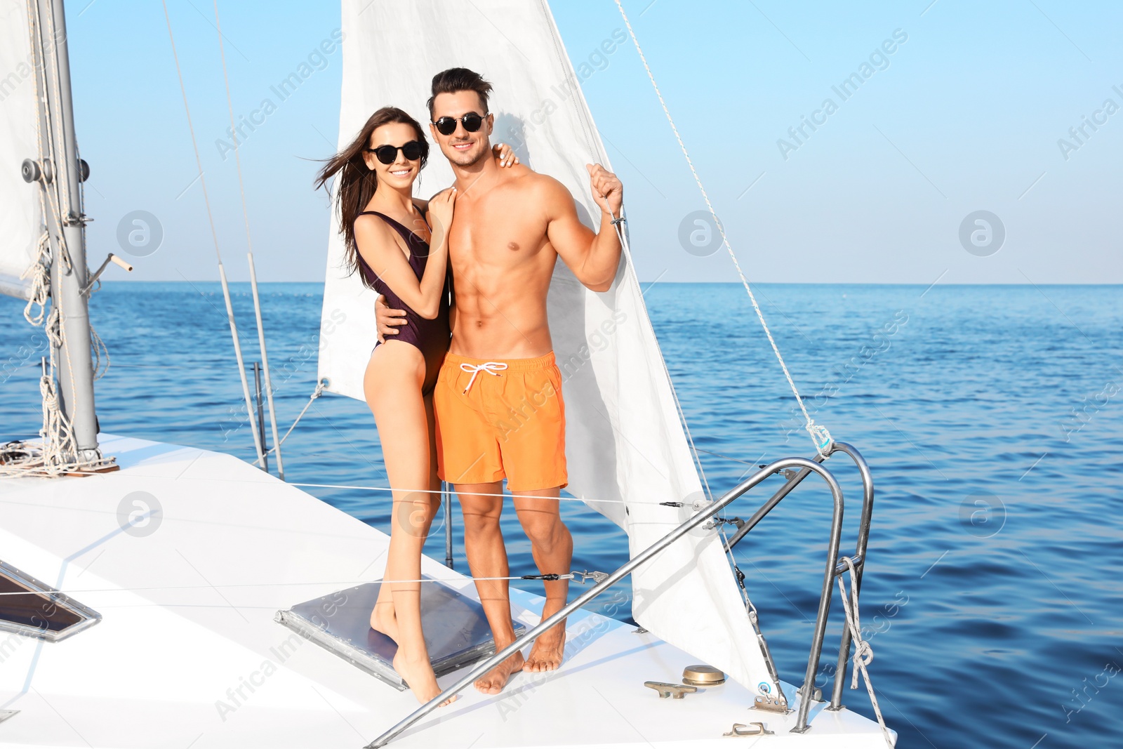 Photo of Young man and his beautiful girlfriend in bikini on yacht. Happy couple during sea trip