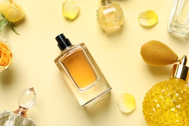 Photo of Flat lay composition with different perfume bottles on light yellow background