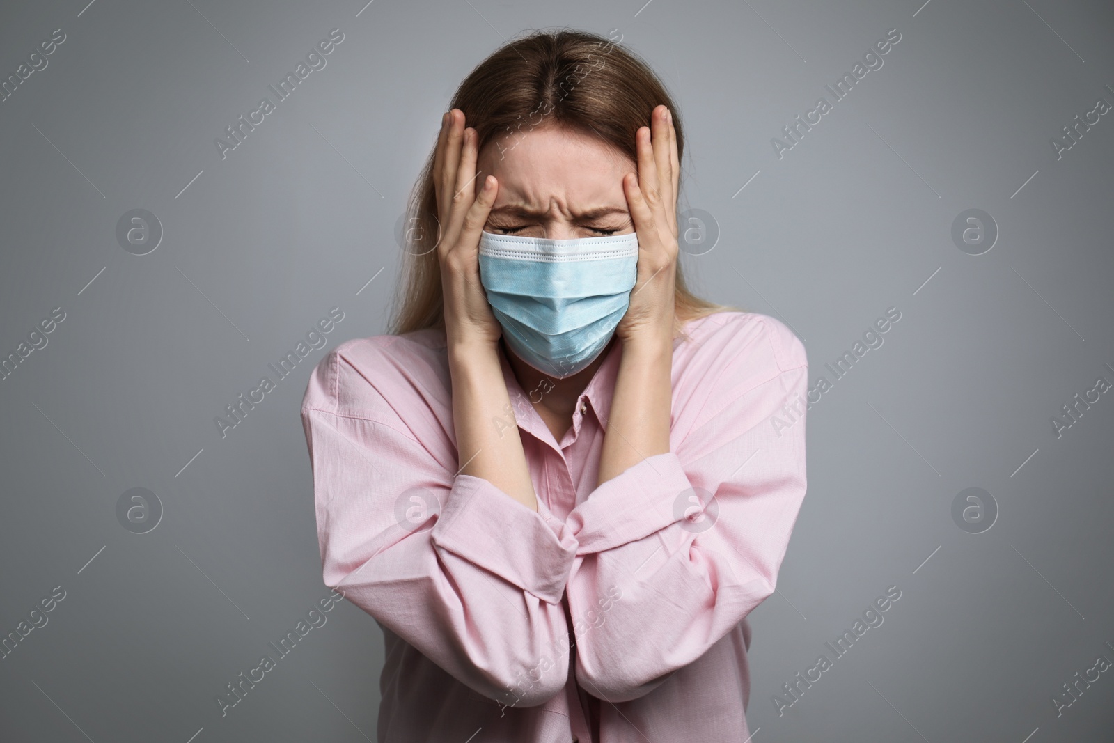 Photo of Young woman in protective mask feeling fear on grey background