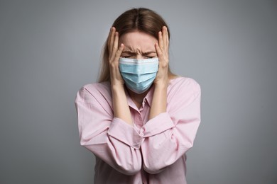 Photo of Young woman in protective mask feeling fear on grey background
