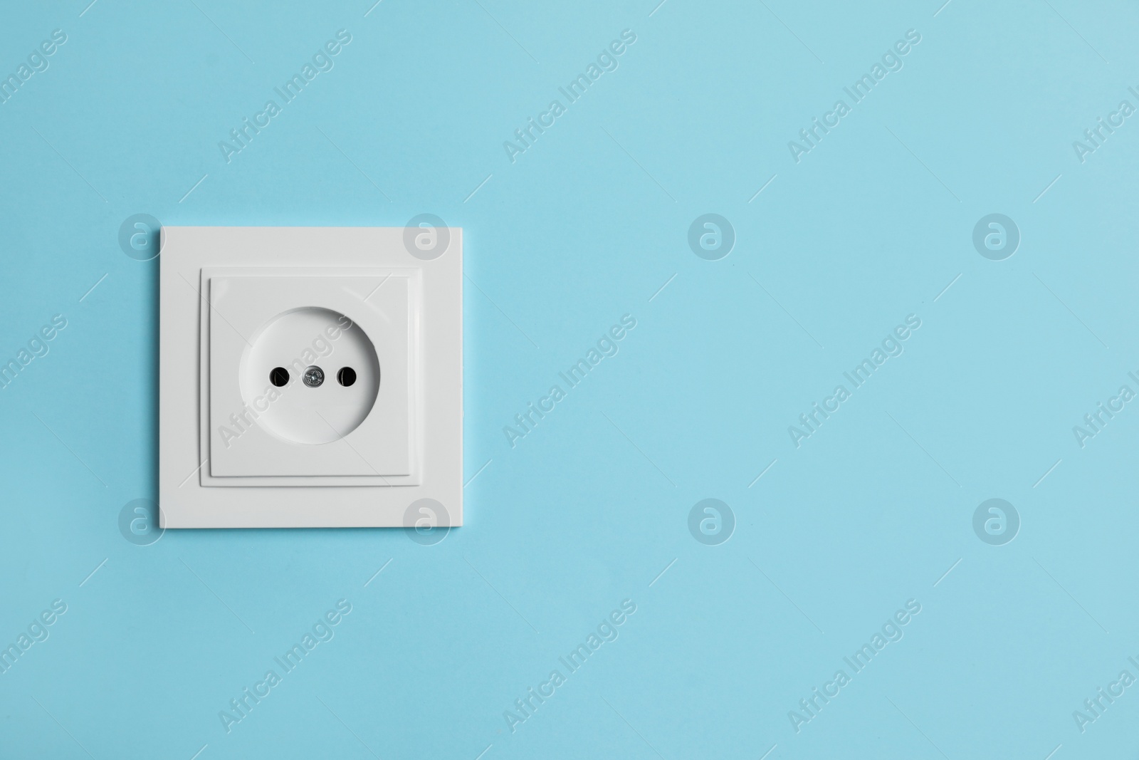 Photo of Power socket on light blue wall, space for text. Electrical supply