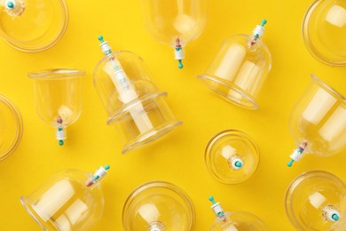 Photo of Plastic cups on yellow background, flat lay. Cupping therapy
