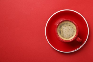 Tasty coffee in cup on red background, top view. Space for text