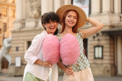 Photo of Happy friends with pink cotton candies on city street