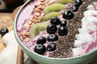 Photo of Delicious acai smoothie with fruits and chia seeds in bowl, closeup
