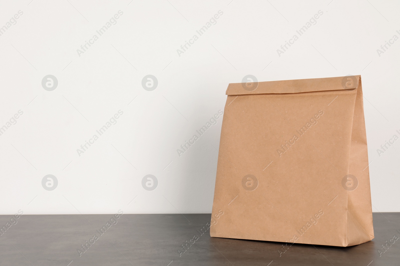 Photo of Paper bag on table against white wall. Mockup for design