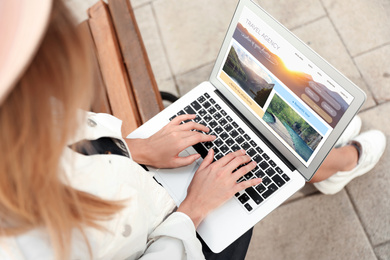 Image of Woman using laptop to plan trip, above view. Travel agency website