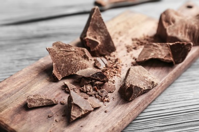 Pieces of delicious dark chocolate on wooden board