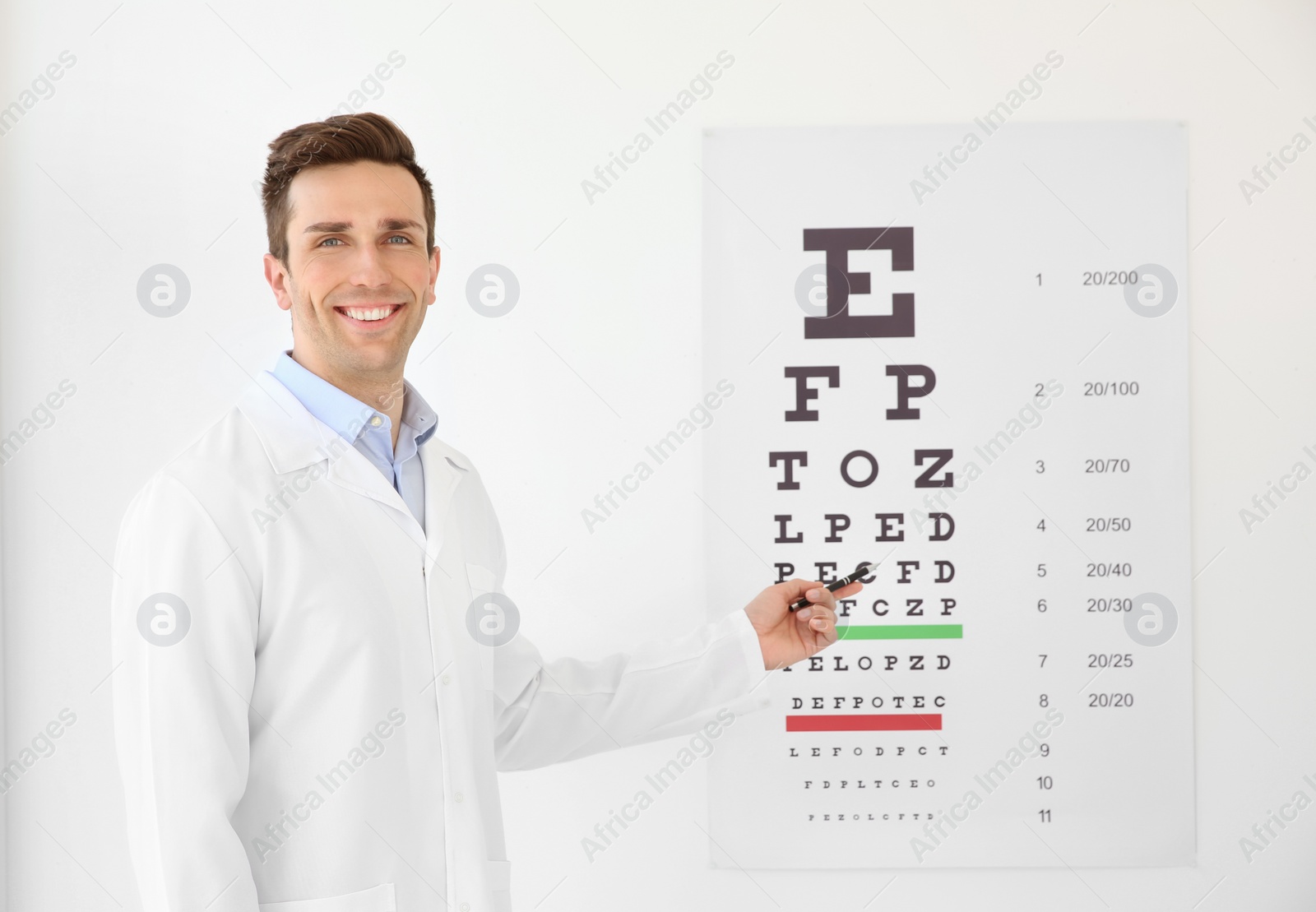 Photo of Young ophthalmologist near eye chart indoors