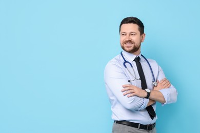 Photo of Portrait of smiling doctor on light blue background. Space for text