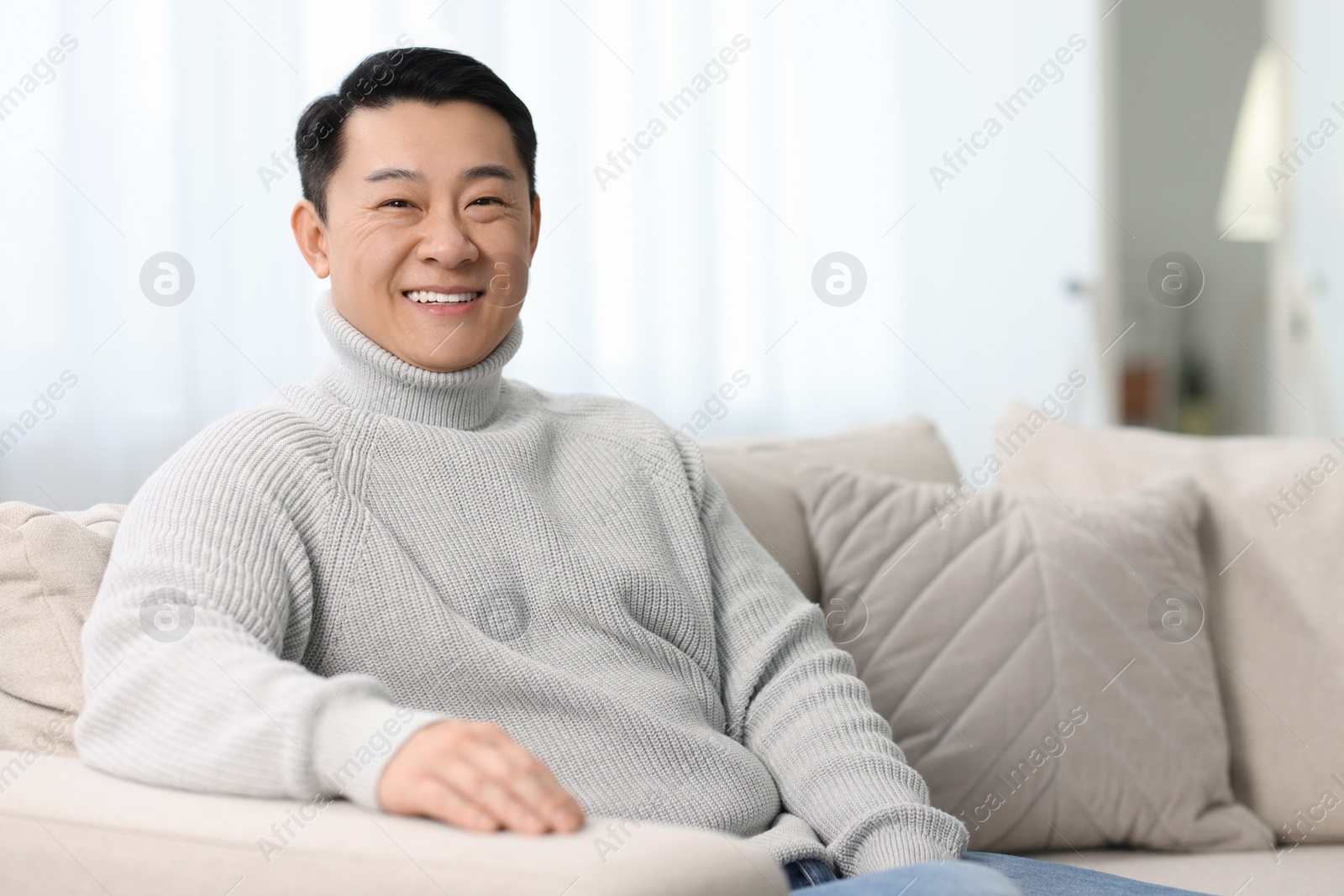 Photo of Portrait of smiling man on sofa indoors. Space for text