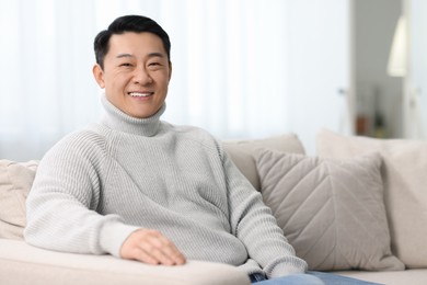 Photo of Portrait of smiling man on sofa indoors. Space for text