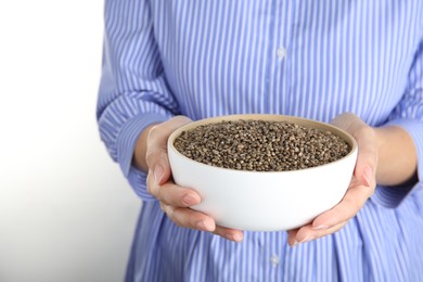 Photo of Woman holding bowl with hemp seeds on white background, closeup