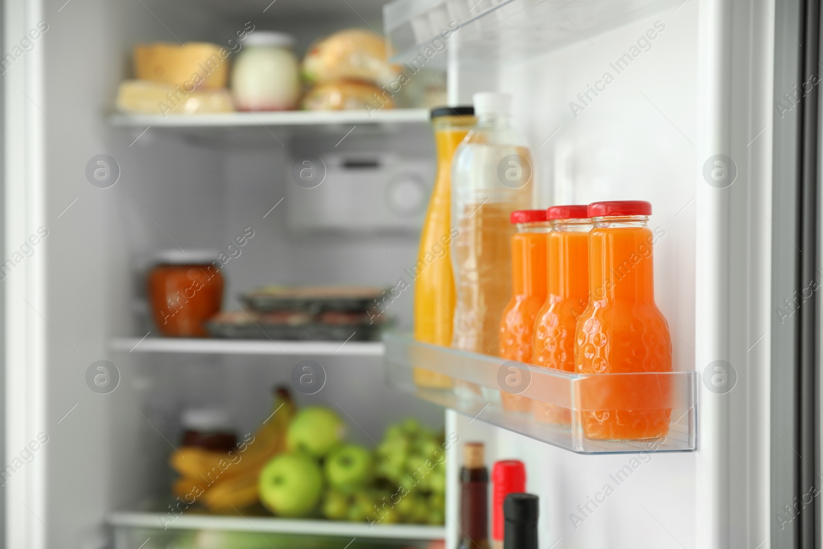 Photo of Bottles of juice on shelf in refrigerator