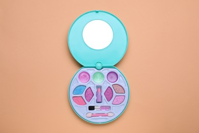 Photo of Children's kit of decorative cosmetics on pale orange background, top view