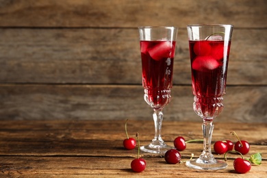 Photo of Delicious cherry wine with ripe juicy berries on wooden table. Space for text