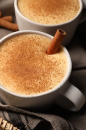 Delicious eggnog with cinnamon in wicker basket, closeup