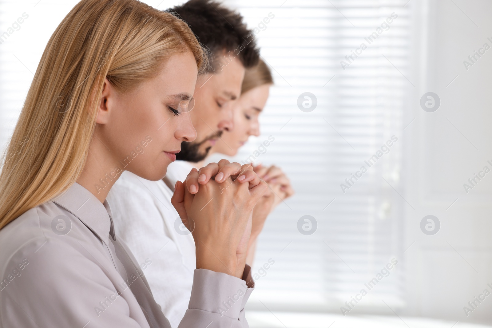 Photo of Group of religious people praying together indoors. Space for text