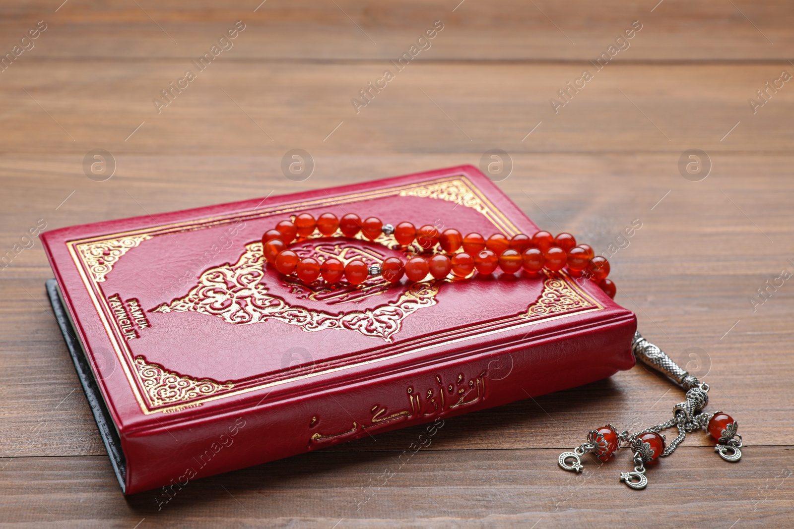 Photo of Muslim prayer beads and Quran on wooden table, closeup