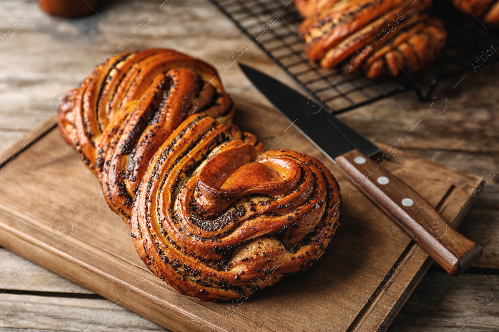 Photo of Tasty sweet bun with poppy seeds on wooden table