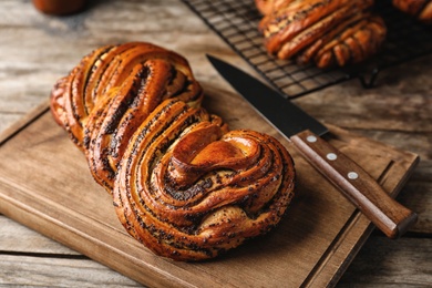 Tasty sweet bun with poppy seeds on wooden table