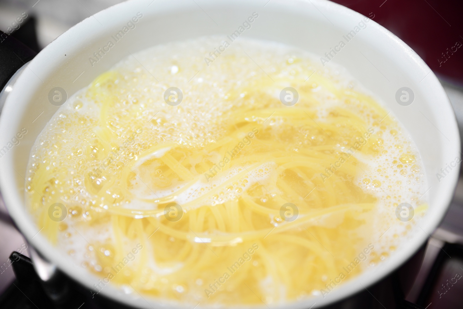 Photo of Cooking pasta in saucepan on stove, closeup