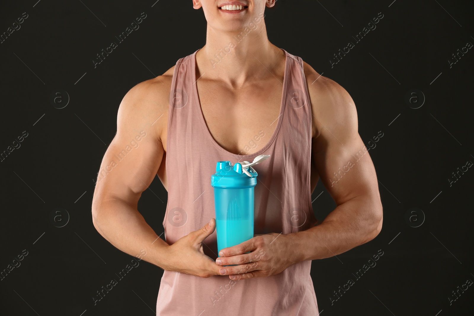 Photo of Athletic young man with protein shake on black background, closeup