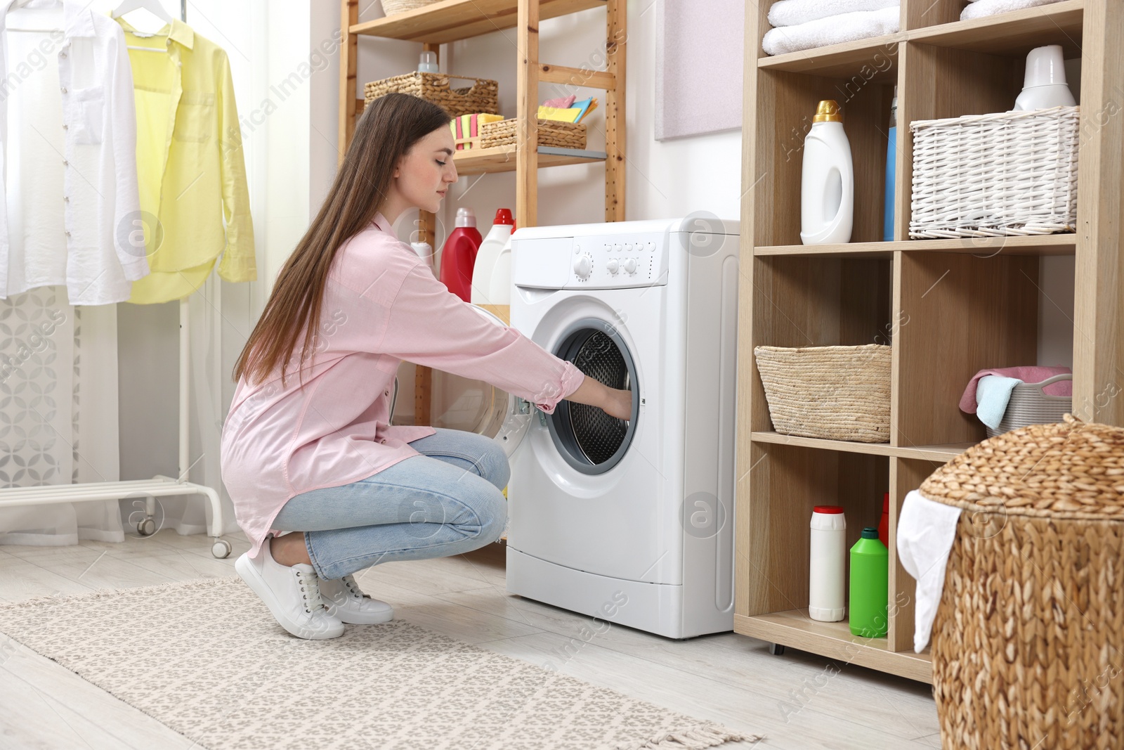 Photo of Beautiful young woman near washing machine in laundry room