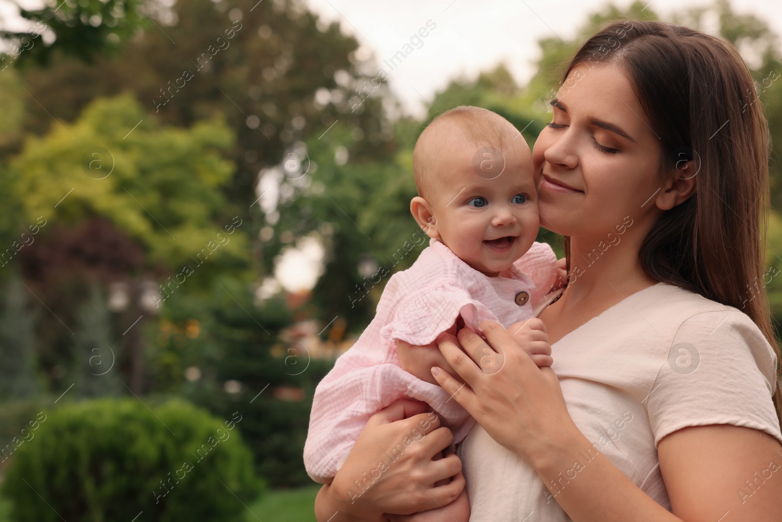 Photo of Happy mother with adorable baby walking in park on sunny day, space for text