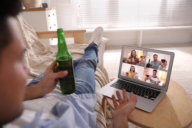 Man with bottle of beer having online party via laptop at home during quarantine lockdown, closeup