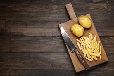 Photo of Whole and cut raw potatoes on wooden table, top view. Space for text