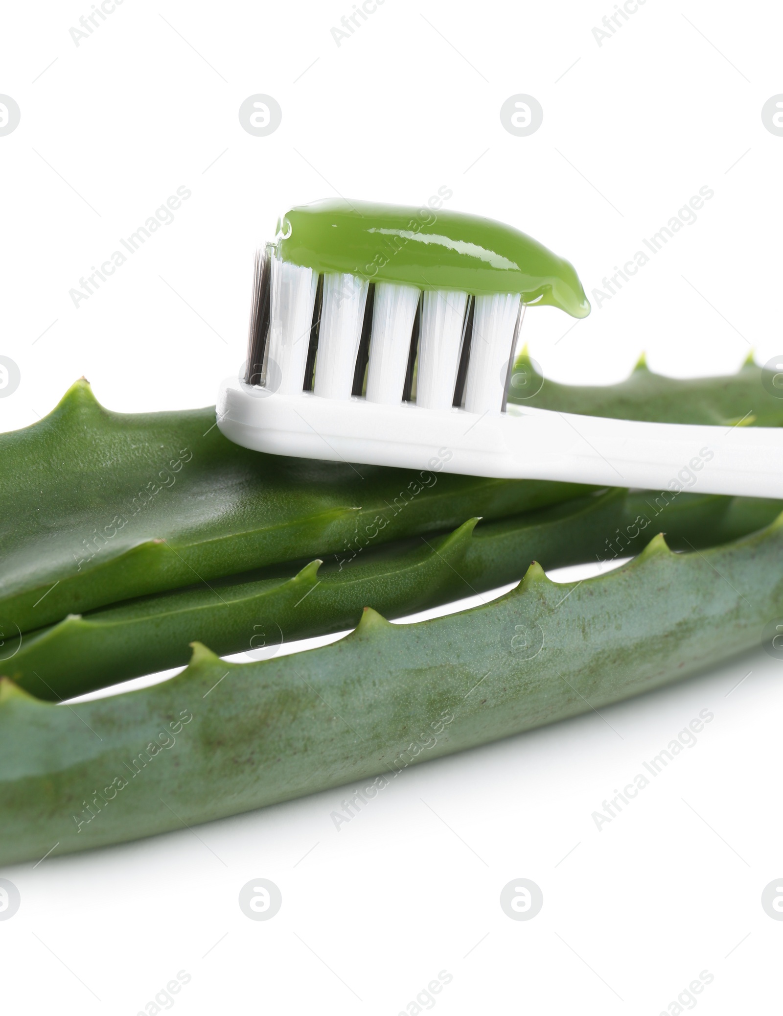 Photo of Brush with toothpaste and green aloe leaves on white background