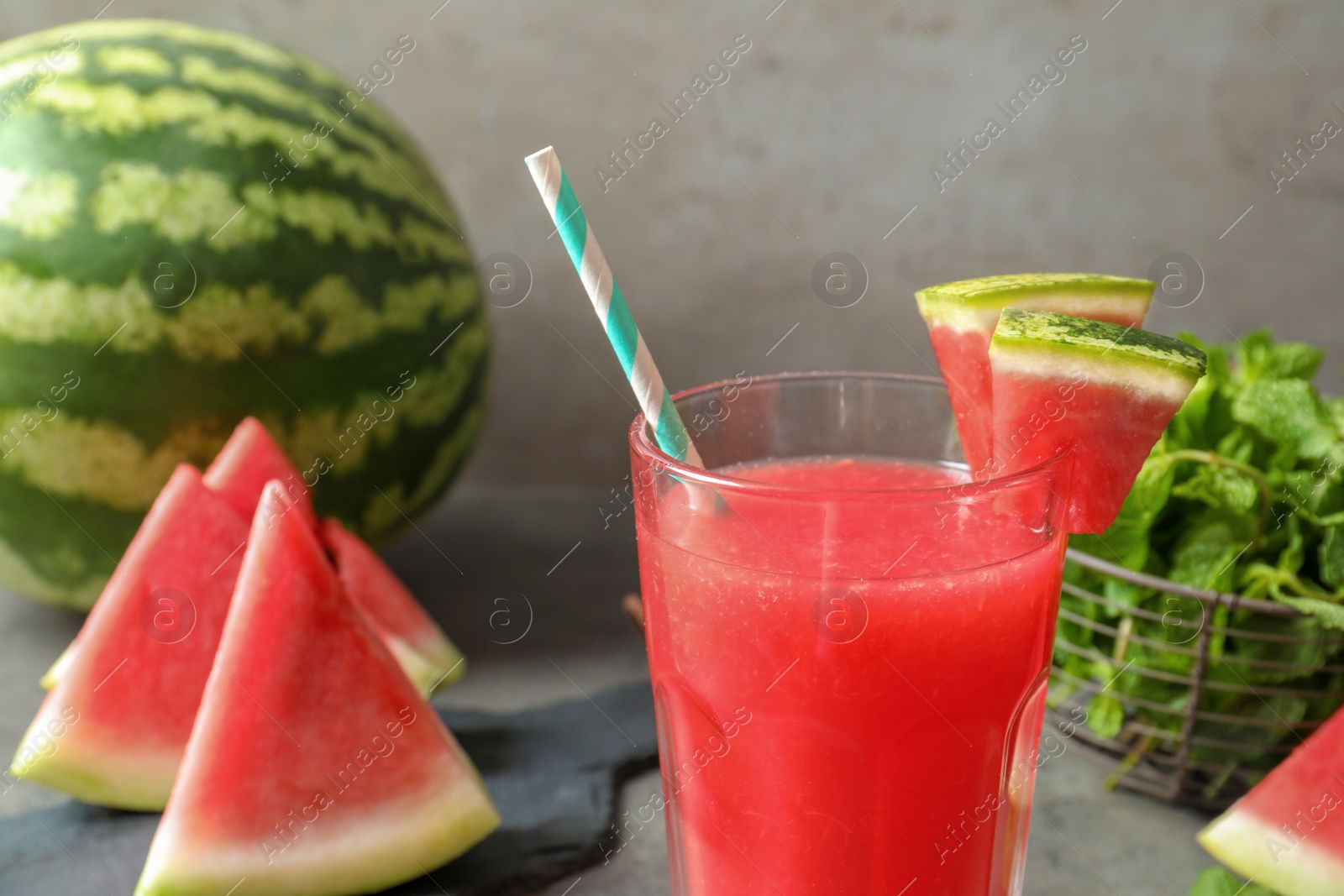 Photo of Summer watermelon drink in glass and sliced fruit on table, closeup