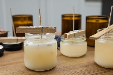 Glass jars with wax on wooden table indoors. Handmade candles