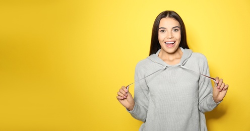 Photo of Young woman in warm sweater on yellow background. Space for text