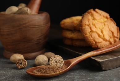 Nutmeg powder and seeds on grey table, closeup