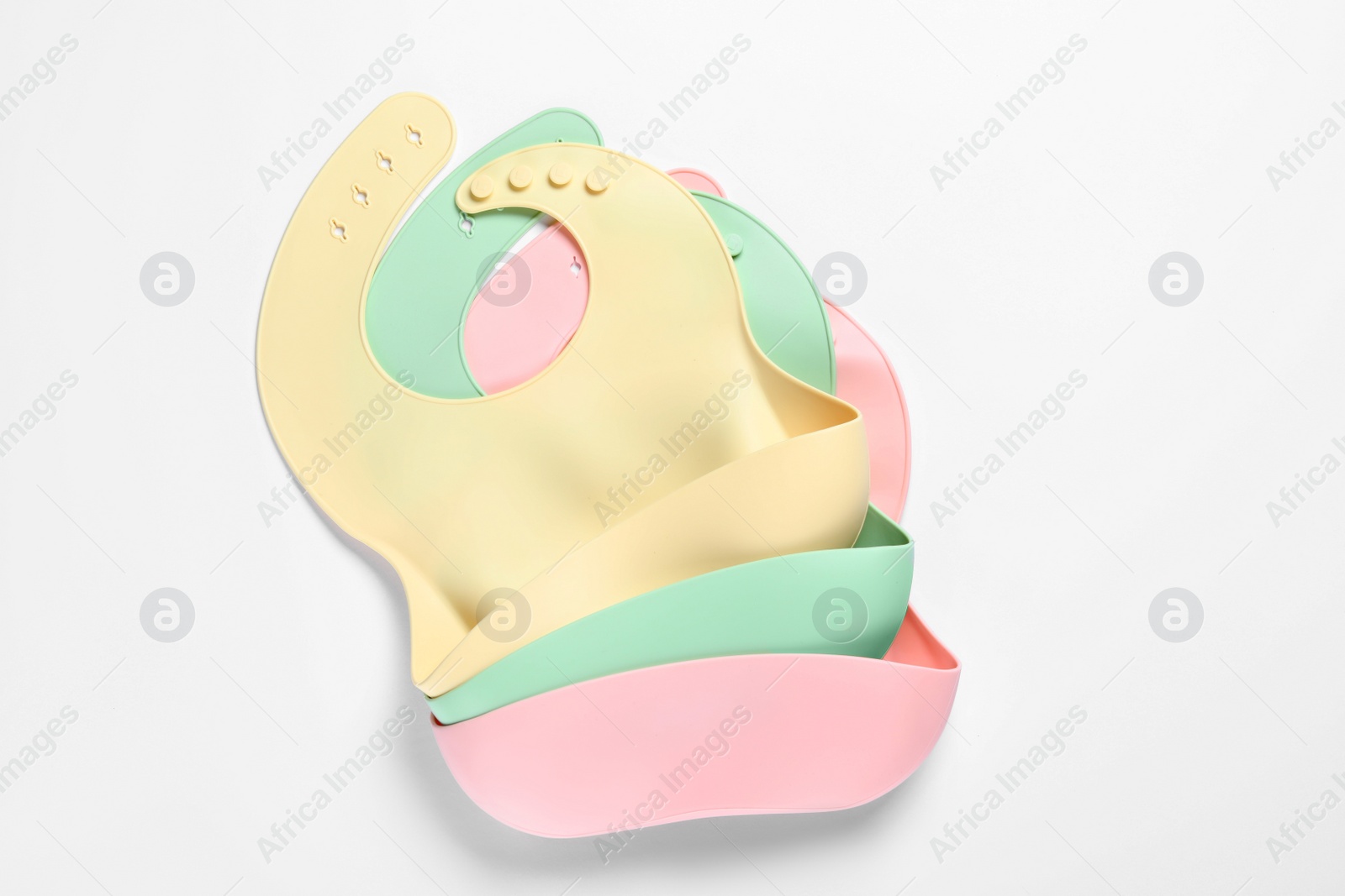 Photo of Color silicone baby bibs on white background, top view