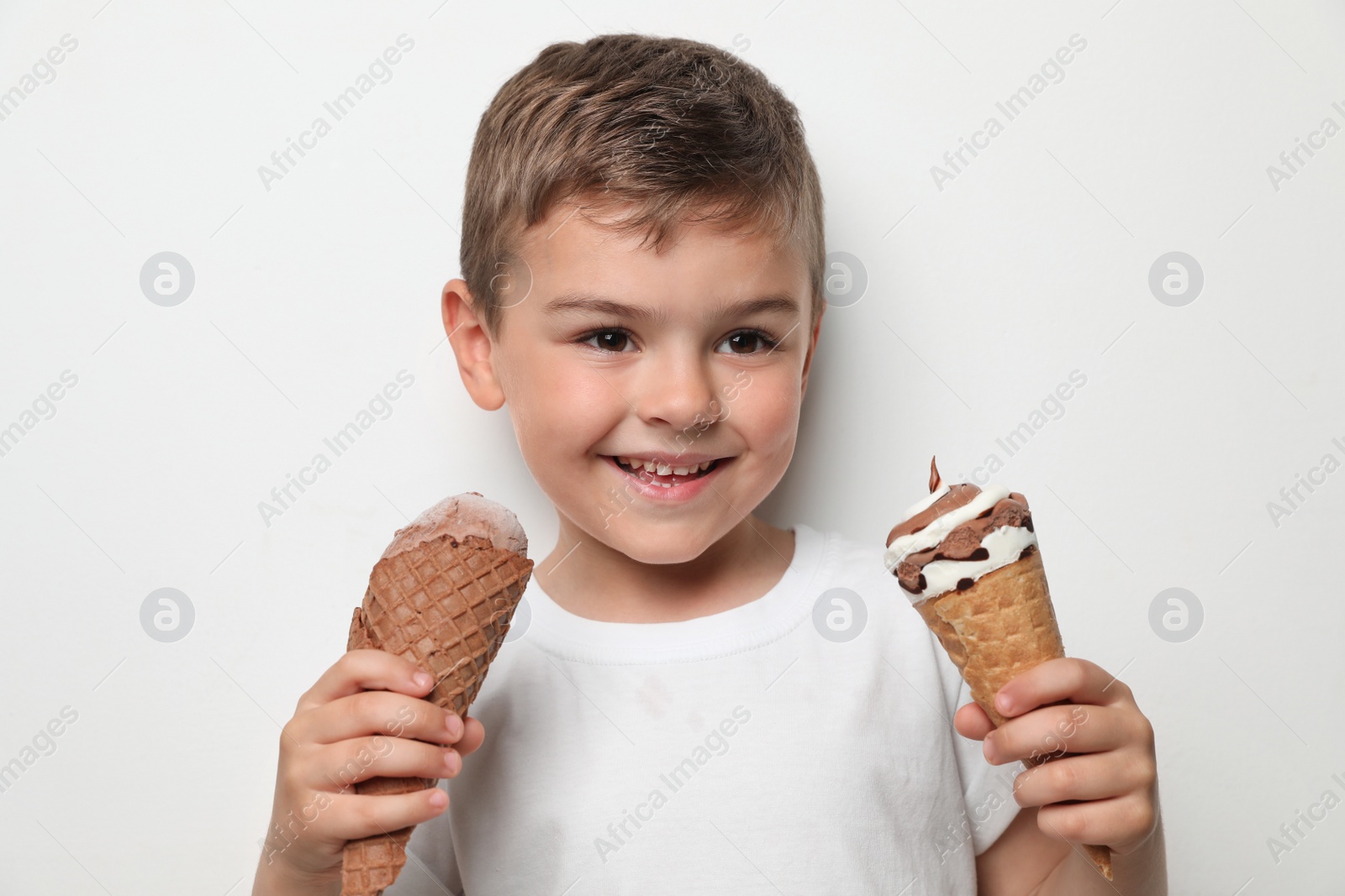 Photo of Adorable little boy with delicious ice creams against light background