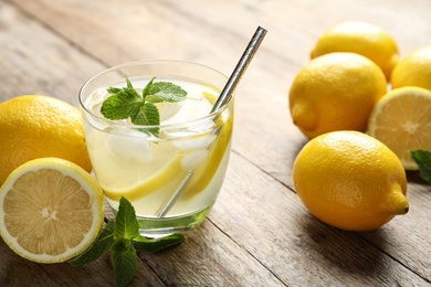 Photo of Natural lemonade with mint and fresh fruits on wooden table, closeup. Summer refreshing drink